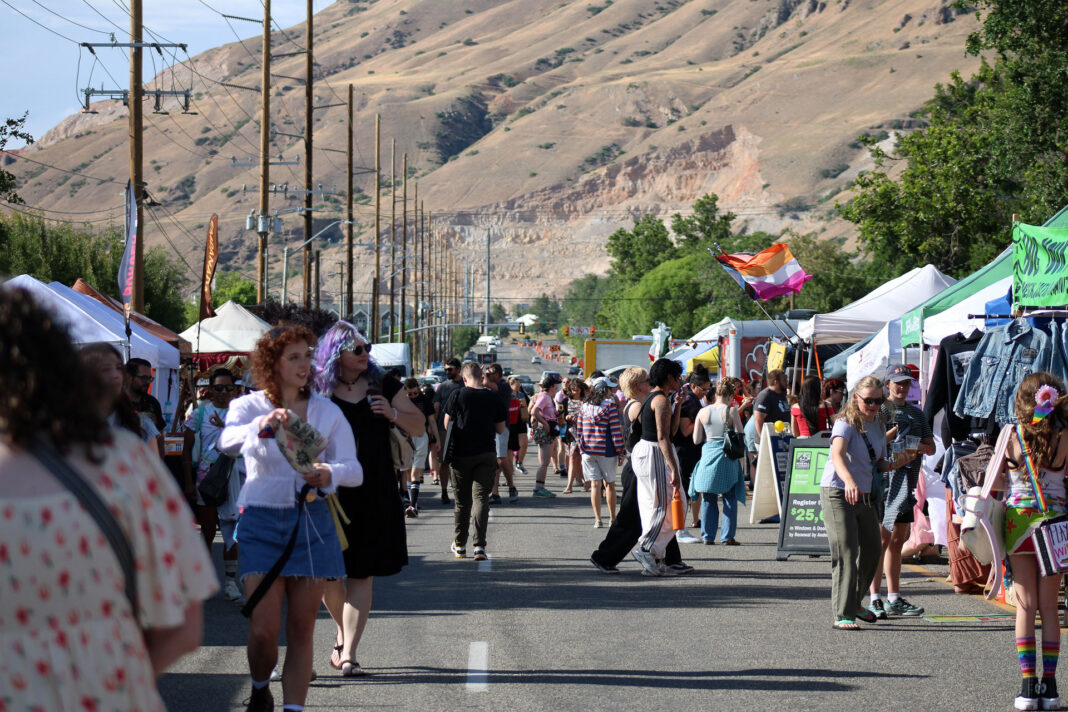 Festivalgoers walk past vendor booths on a city street