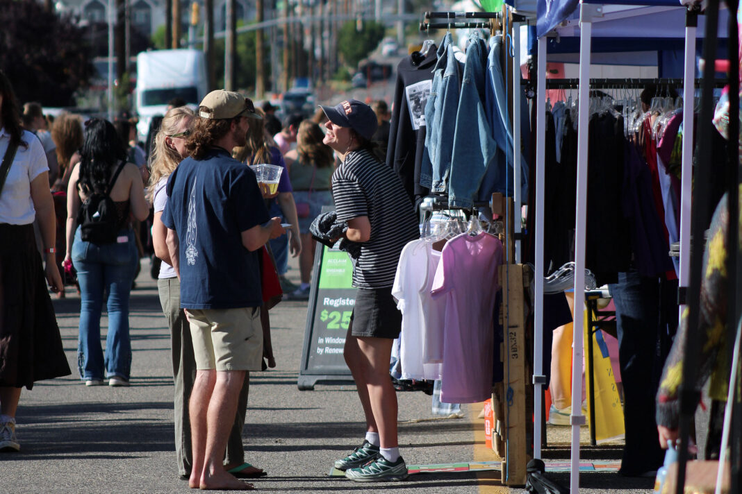 Festivalgoers talking and browsing vendor booths on a city street