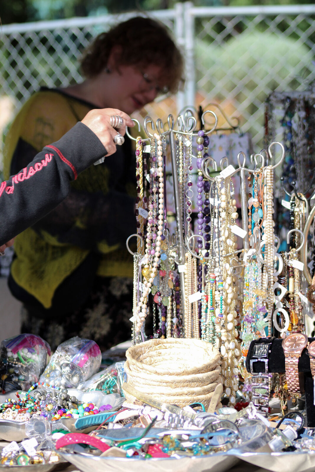 Woman's hand turning a display rack of fashion accessories displayed on a table