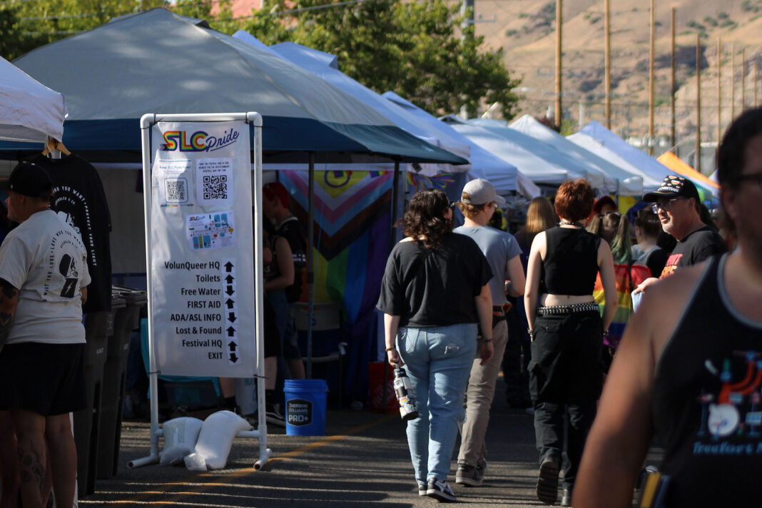 Festivalgoers walking past vendor booths and a venue directory