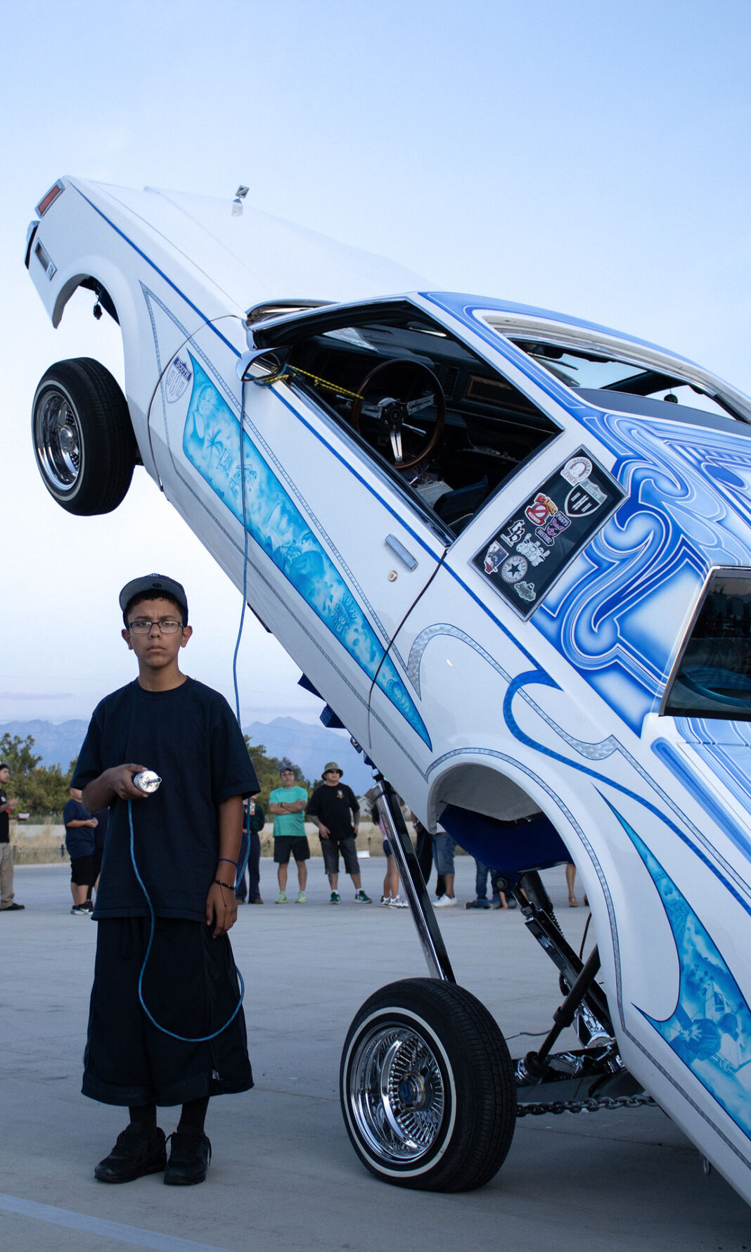 Young man holding controls while standing next to his custom car