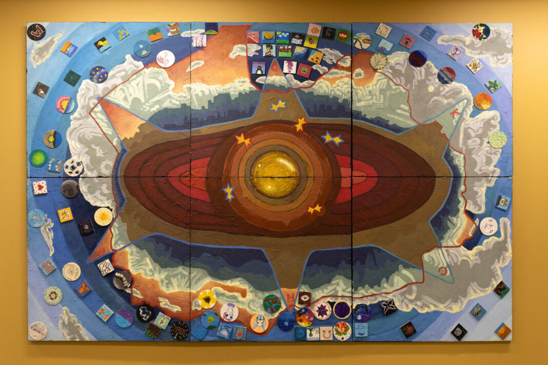 Mural depicting the inner Earth and mountains with buttons and badges on the outer edges
