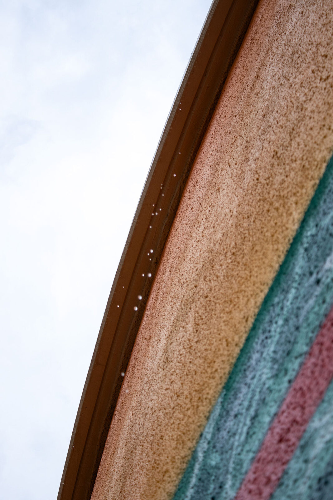 Raindrops dripping off of a curved edge of a structure