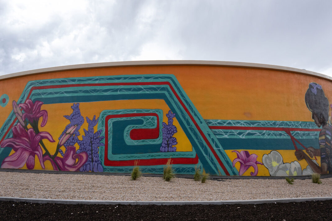 Painted mural spans curved wall of a water tank