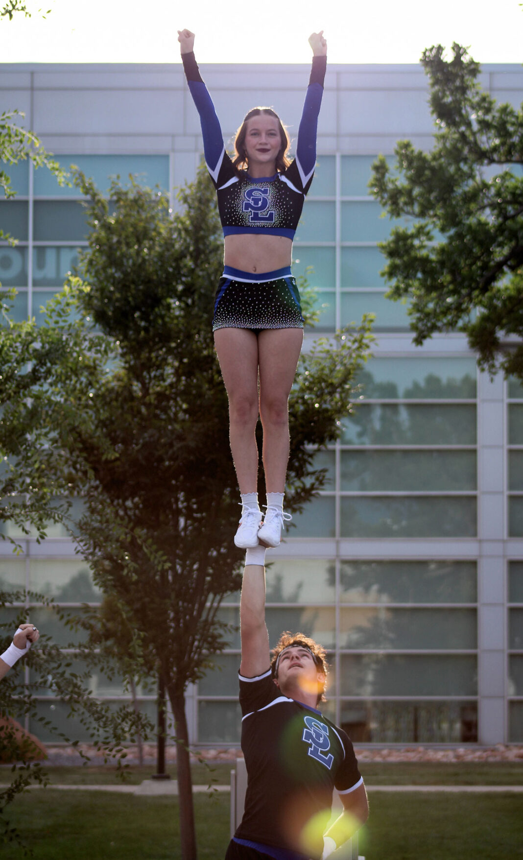 Female cheerleader standing on male cheerleader's hand