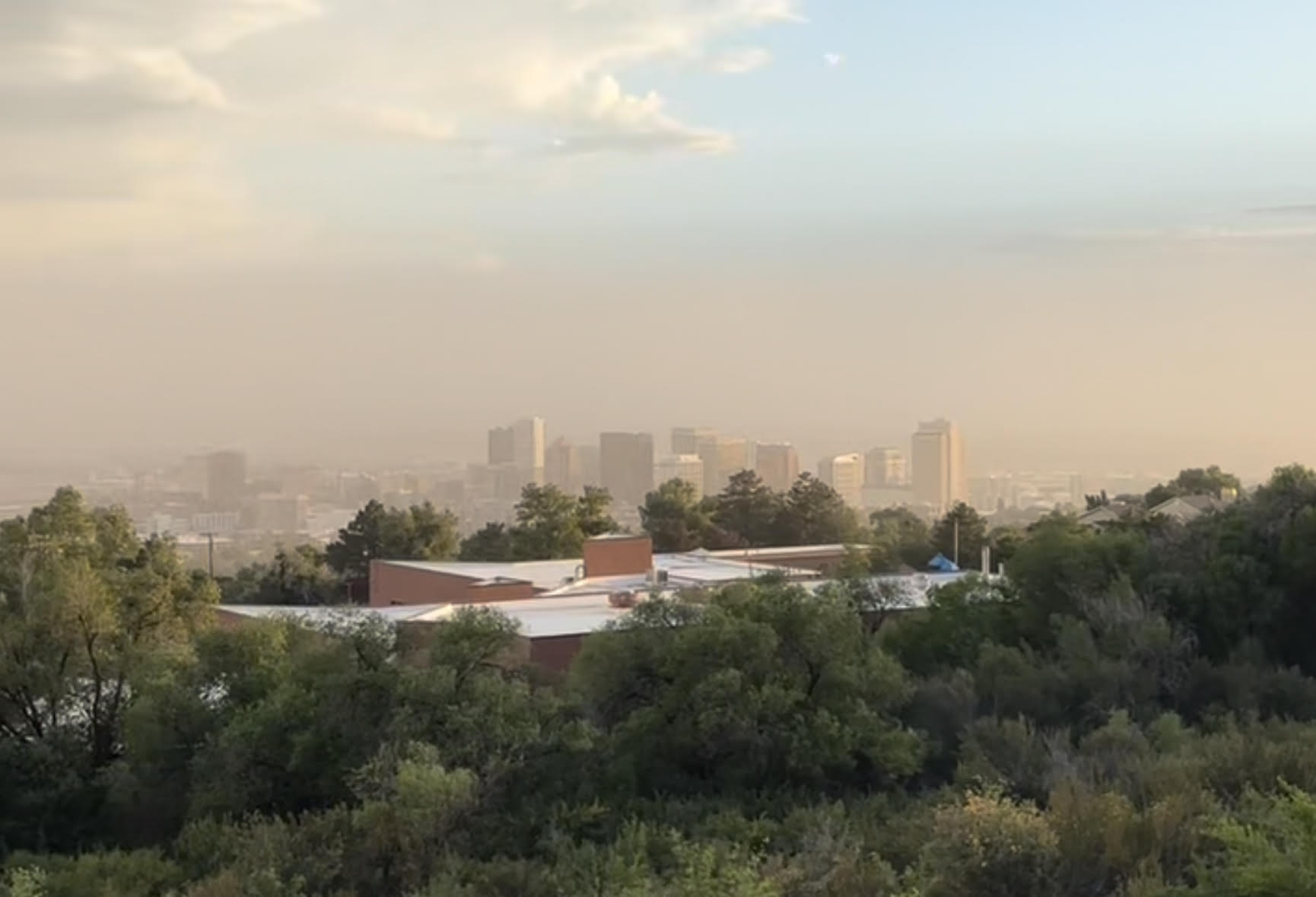 Cityscape shrouded by dust under a blue sky