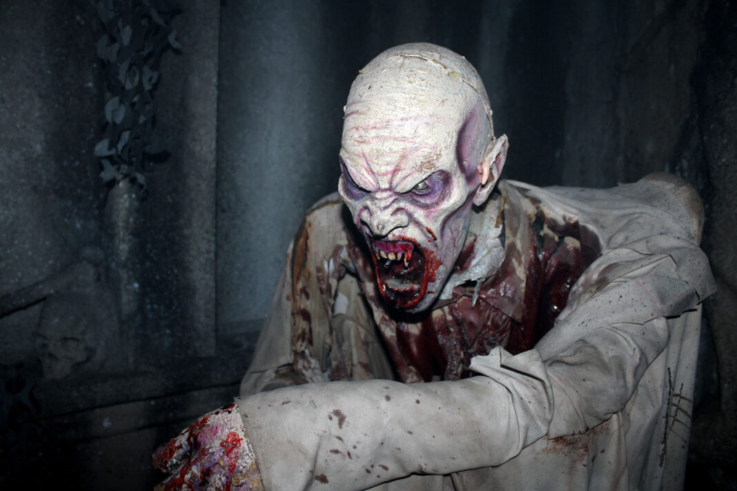 A ghoul with bloody ravenous teeth lunging at guests