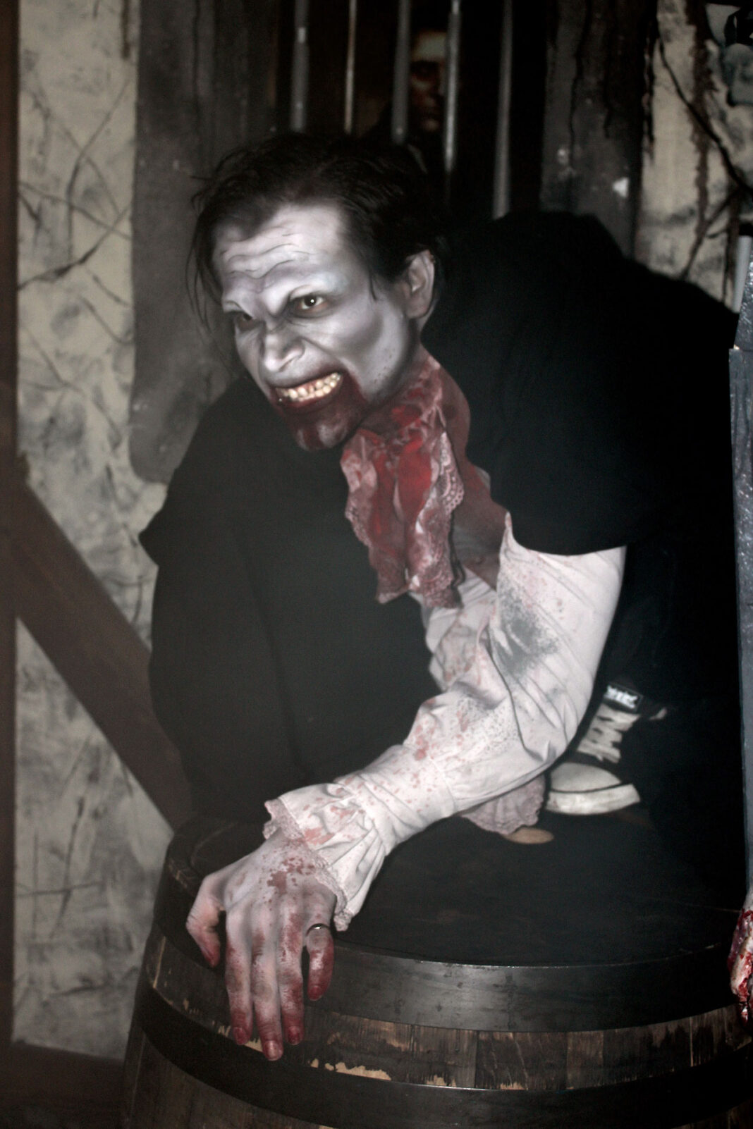 Vampire scaring guests while perched on an old oak barrel