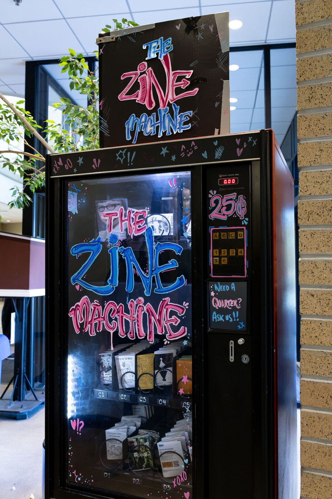 Portrait style photo of the Zine Machine, mainly colors of blue and pink