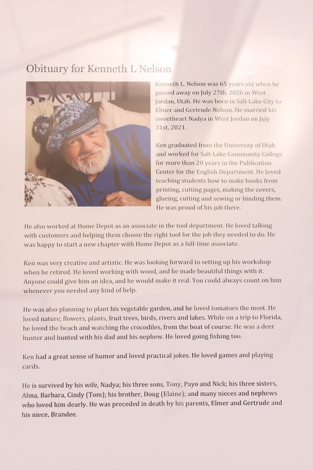 Portrait style photo of a framed copy of the Obituary of Kenneth L. Nelson