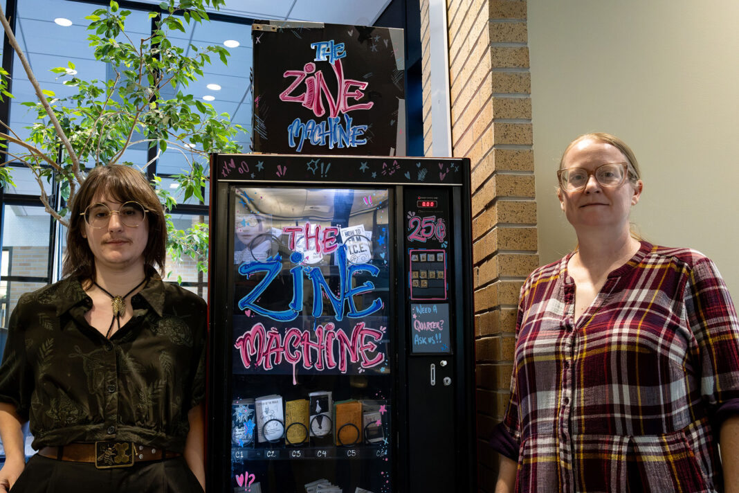 Landscape style photo of Oliver and Brenda standing next to the Zine Machine