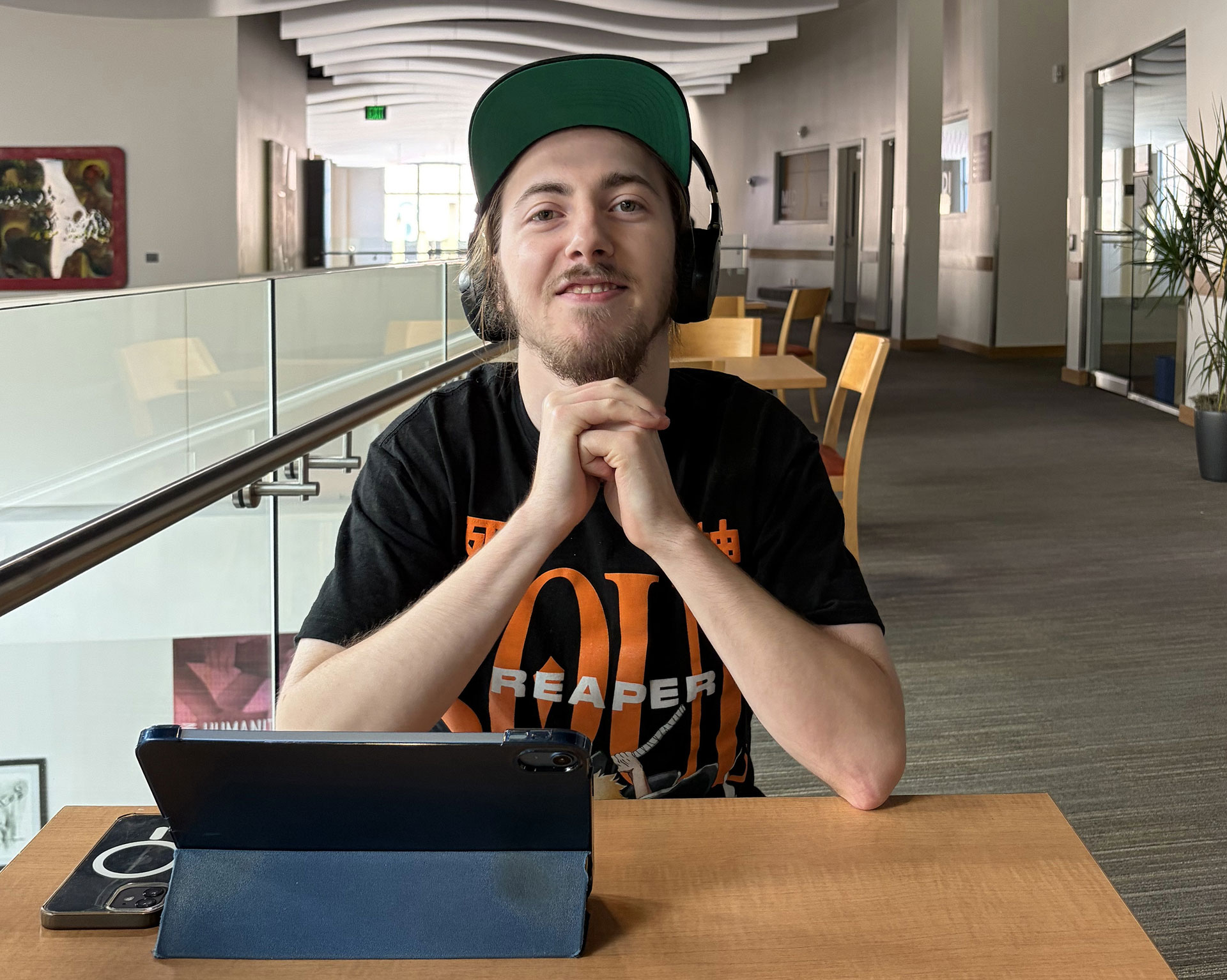 Alex smiling with folded hands while wearing headphones