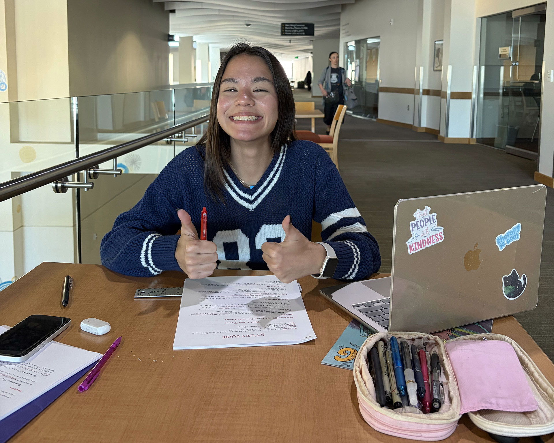 Stephanie smiling and giving two thumbs up while studying