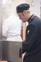 A culinary student is placing a pan into a oven during breakfast service at the Utah State Capitol cafeteria.