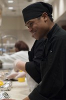 A culinary student at the Grill in the Utah State Capitol Cafeteria is smiling as they serve the breakfast rush crowd.