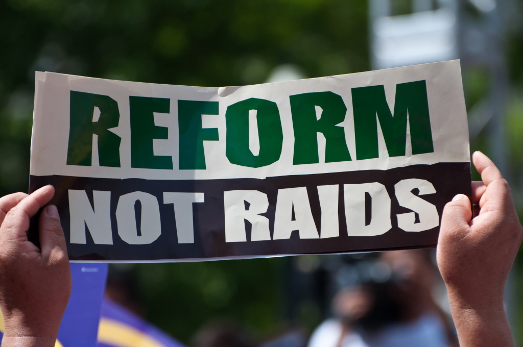 Immigration expert shares information on reform "Reform not raids" protest sign