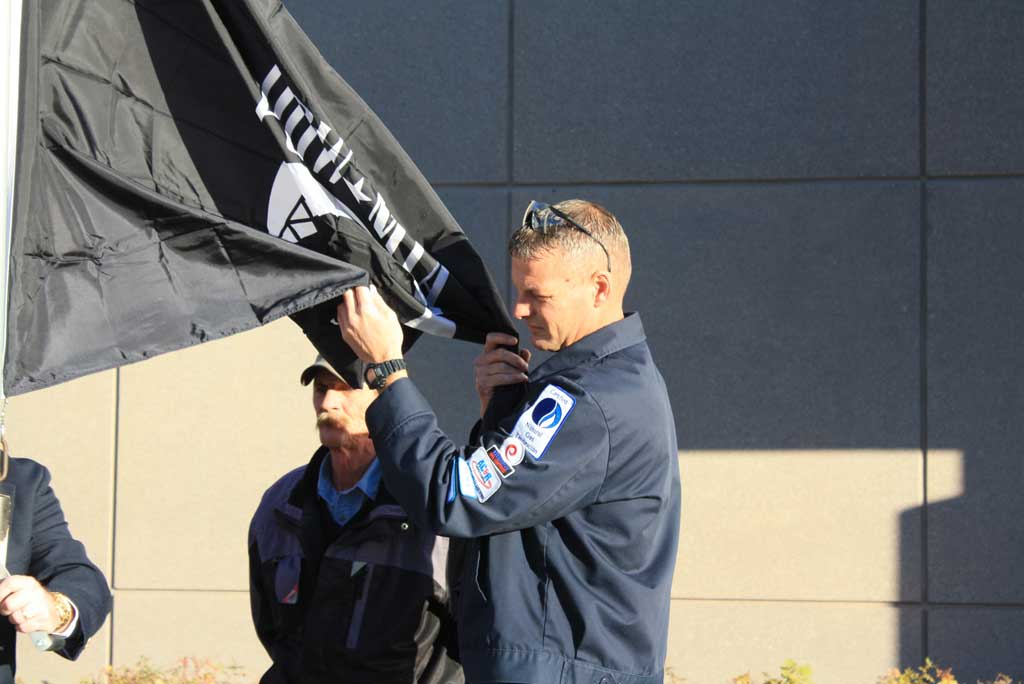 Meadowbrook Campus appeals to veterans James Cantrell hoisting the somber black and white POW flag.