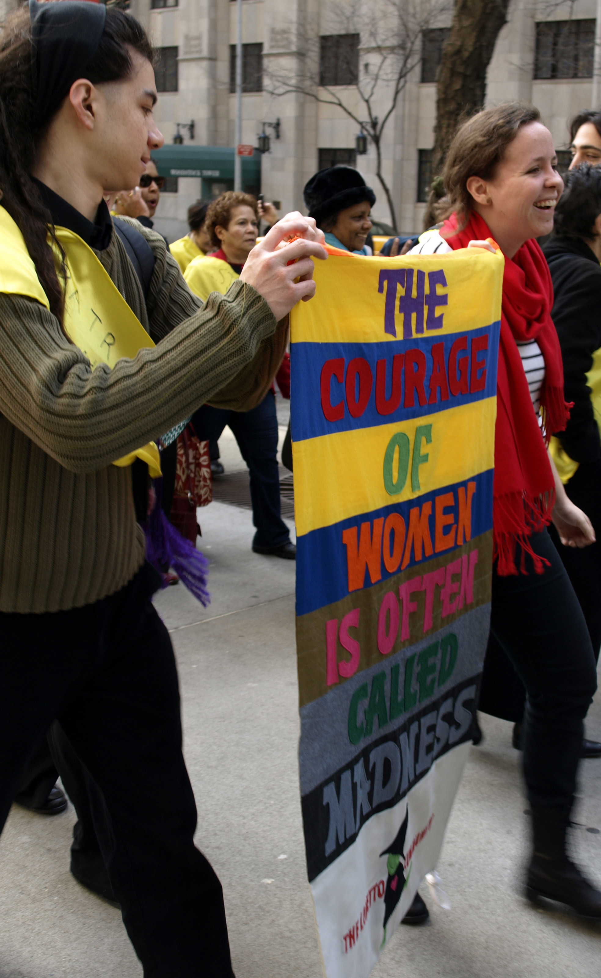 A celebration of women March participants wear yellow sashes to show solidarity.